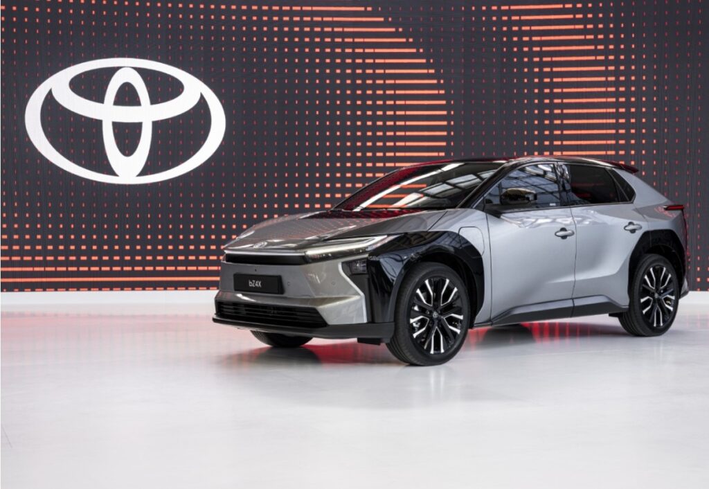 Toyota bZ4X eléctrico gris en exhibición, SUV 100% eléctrico de Toyota con diseño moderno y logo de la marca al fondo.